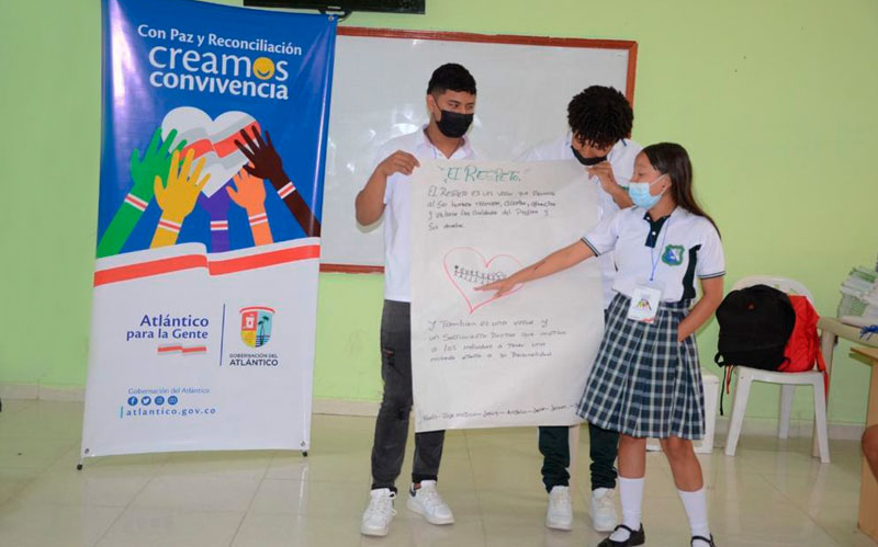 Fotografía de estudiantes exponiendo cartelera referente a a la Convivencia