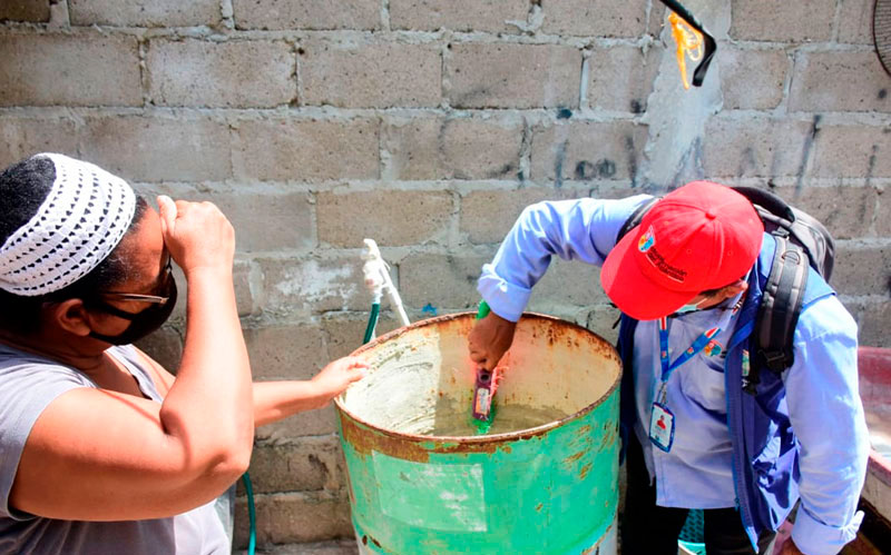 Fotografía funcionario de Secretaria de Salud revisando tanque de agua para detectar mosquito trasmisor del Dengue