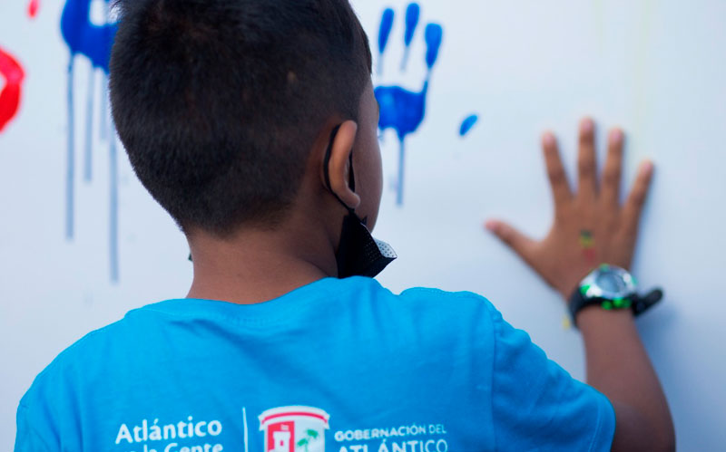 Fotografía niño pintando su mano en mural simbólicamente