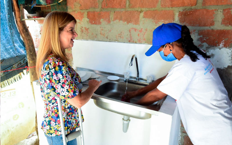 Fotografía gobernadora Elsa Noguera en cocina abriendo la pluma del agua de una beneficiaria de las obras de mejoramiento