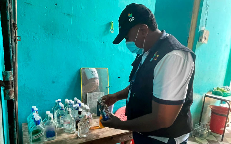 Fotografia de funcionario revisando botellas de alcohol de contrabando