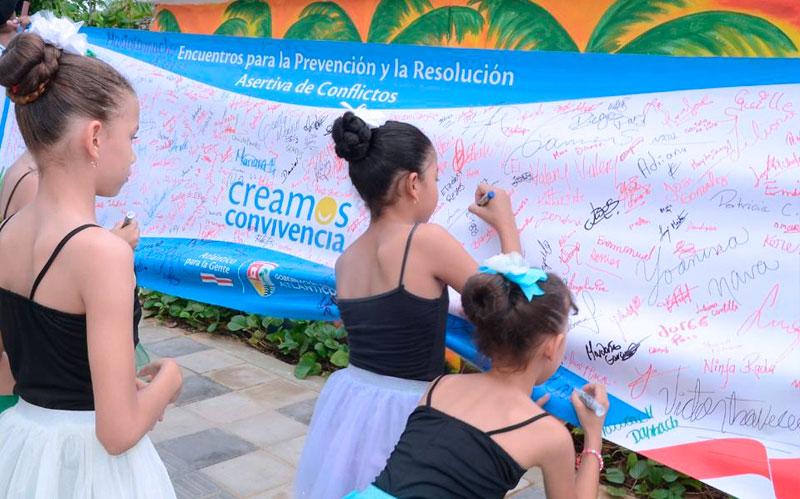 Fotografía niñas participantes escribiendo mensaje en mural