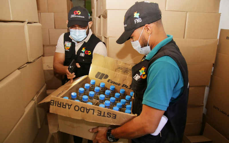 Fotografía funcionarios con caja decomisada de alcohol adulterado