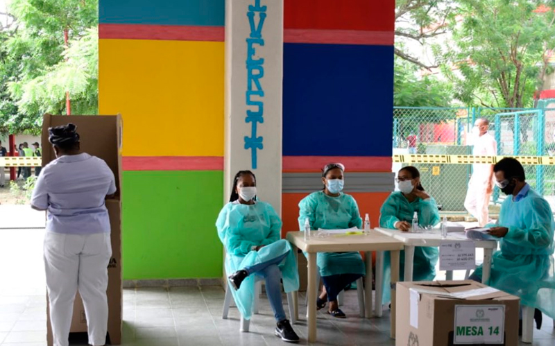 Foto de personas en cubículo realizando su voto