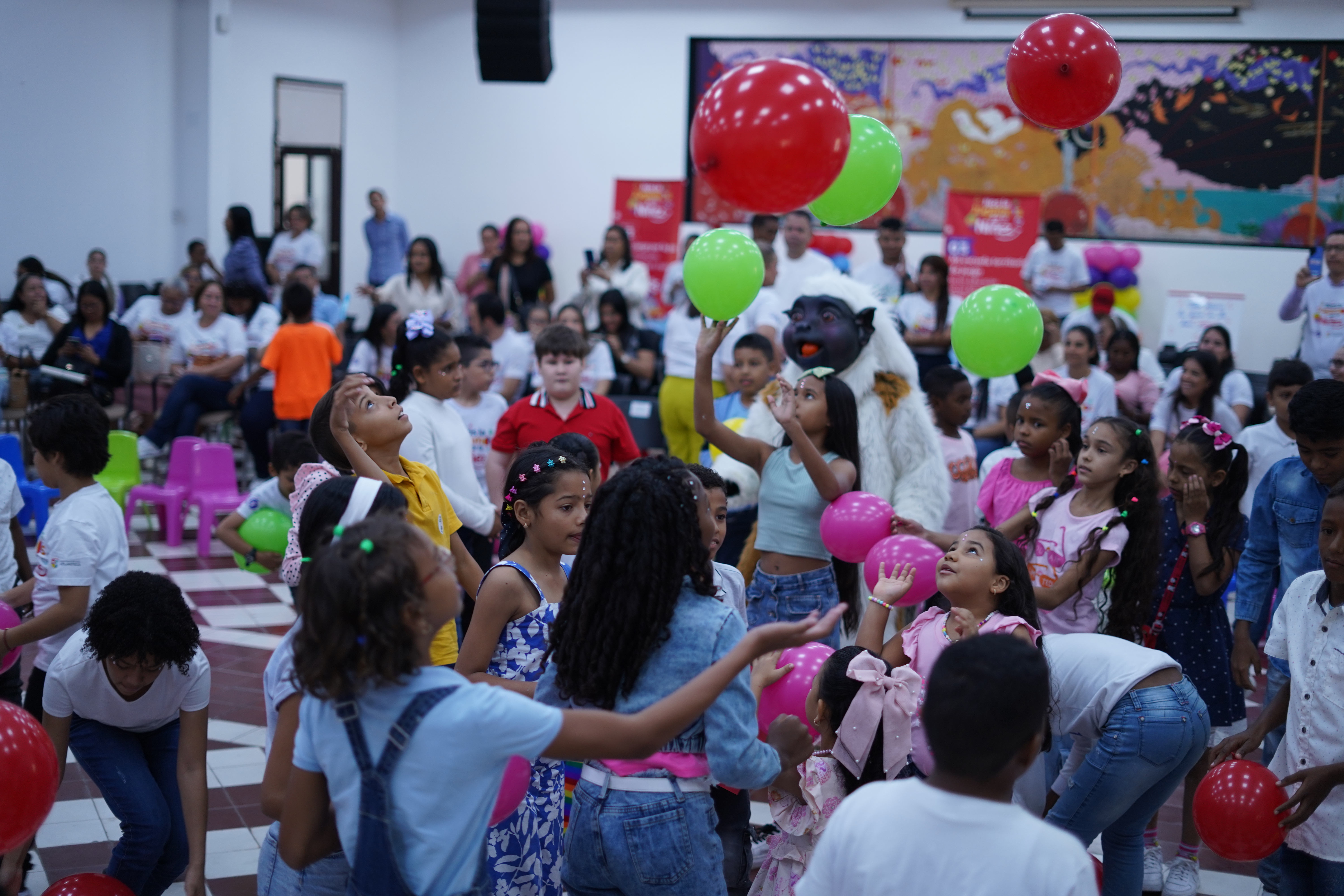 Foto de niños y niñas jugando con globos y un disfraz de Mono Tití Cabeciblanco.